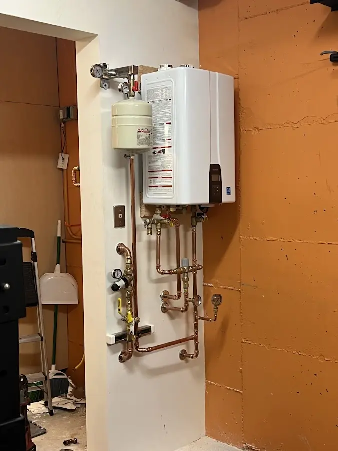 Plumbing technician inspecting water heater connections in Lyons